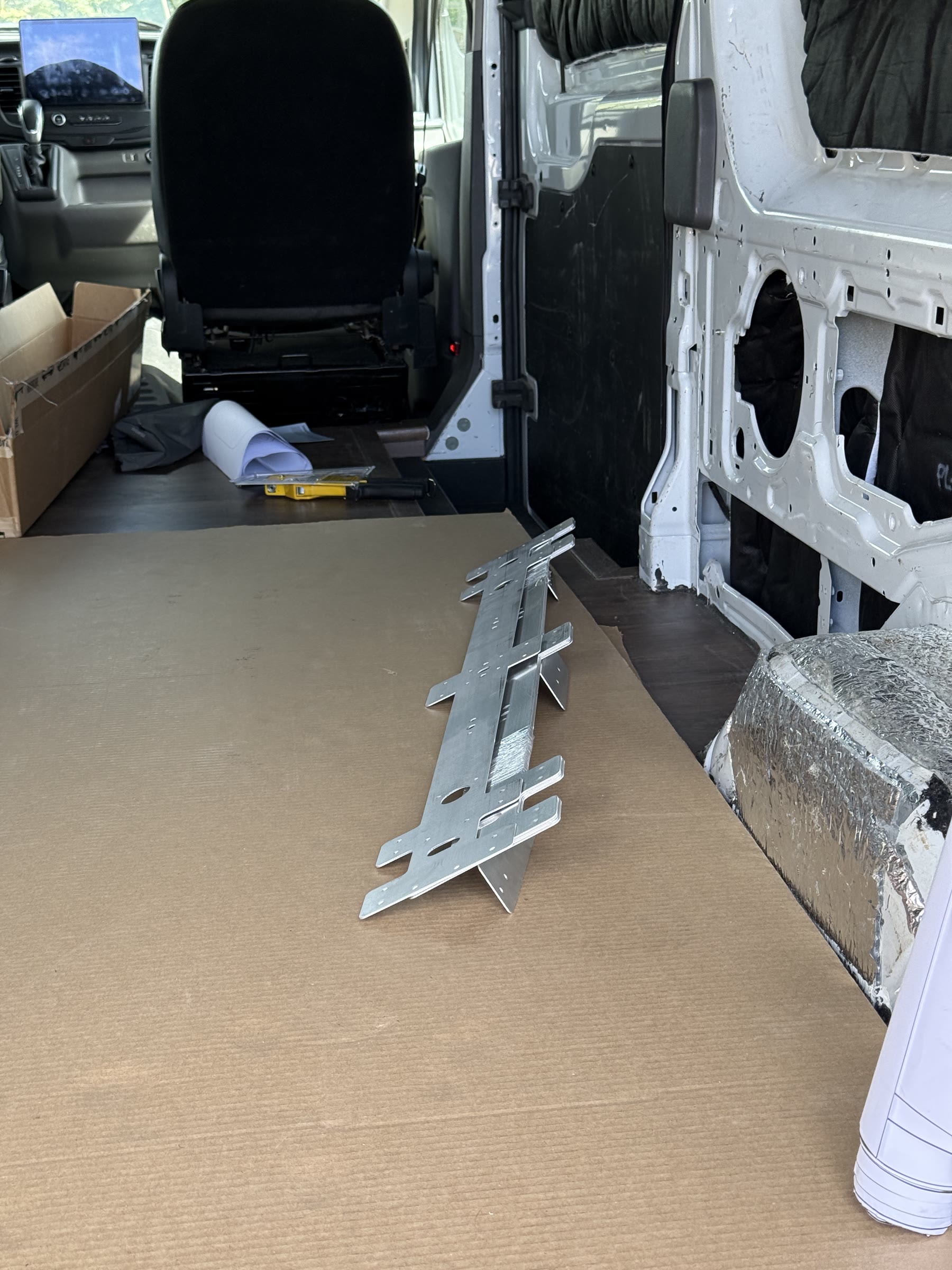 Ceiling support parts laid out on the finished floor of the unfinished Transit